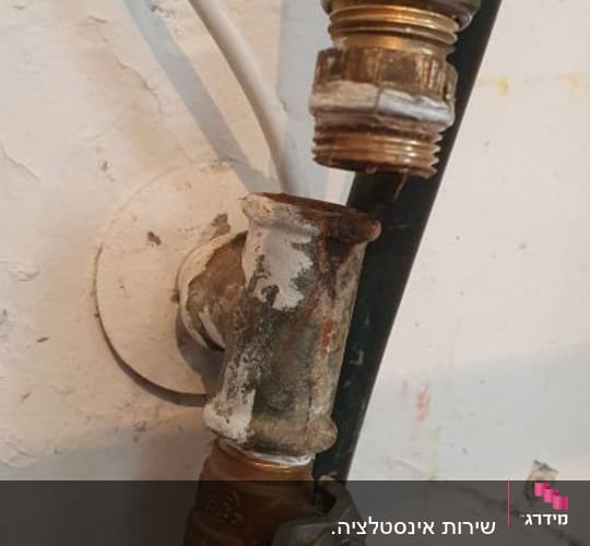 צינור מים עם ברז כחול וחיבורים חלודים